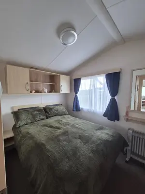 a bedroom with a large bed and a window at Cosy Perranporth caravan, Cornwall in Perranzabuloe