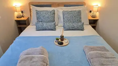 a large bed with blue and white pillows at Cornwall Caravan Retreat 3 Crantock in Crantock