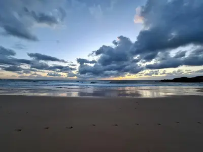 a beach with a cloudy sky and the ocean at St Merryn in St Merryn