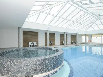 a large swimming pool with chairs and tables in a building at Atlantic Escape in Bude
