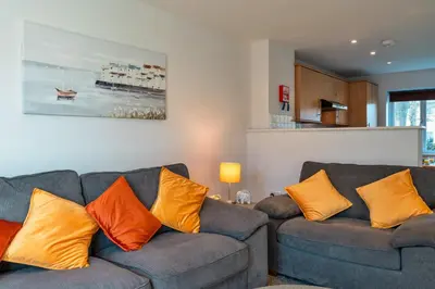 a living room with two gray couches with orange pillows at Finest Retreats - Carworgie Cottage in Newquay