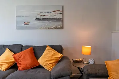 a living room with a gray couch with orange pillows at Finest Retreats - Carworgie Cottage in Newquay