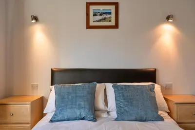 a bedroom with a bed with blue pillows and two night stands at Finest Retreats - Carworgie Cottage in Newquay