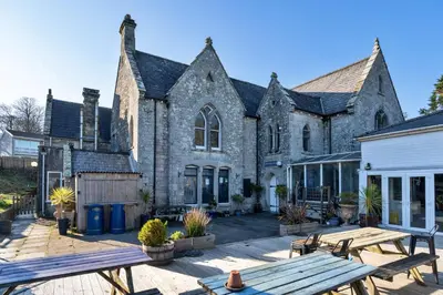 a large stone building with picnic tables in front of it at Finest Retreats - Carworgie Cottage in Newquay