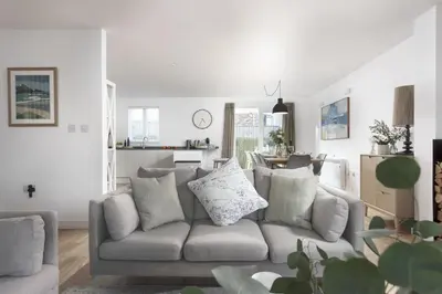 a living room with a gray couch and a kitchen at Carbis Bay Lodge - Spa Facilities & Woodburner in Carbis Bay
