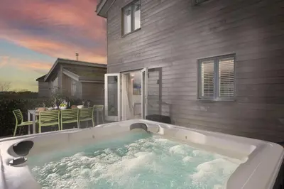 a hot tub in front of a house at Carbis Bay Lodge - Spa Facilities & Woodburner in Carbis Bay