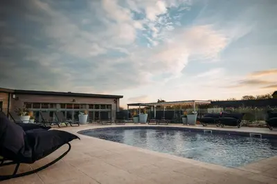 a swimming pool with chairs and a building at Carbis Bay Lodge - Spa Facilities & Woodburner in Carbis Bay