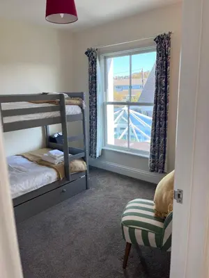 a bedroom with bunk beds and a window and a chair at Trevone Holidays Kohinoor in Padstow
