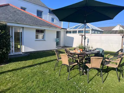 a table and chairs with an umbrella in a yard at Trevone Holidays Kohinoor in Padstow