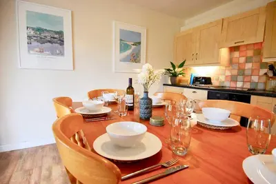 a dining room table with chairs and a table with plates and wine glasses at Riverside farm cottage on private wildlife estate 2-bedrooms in Washaway