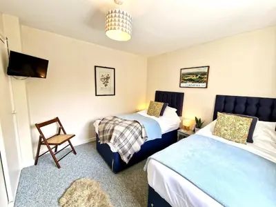 a room with two beds and a tv and a chair at Riverside farm cottage on private wildlife estate 2-bedrooms in Washaway