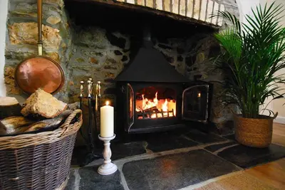 a stone fireplace with a candle in a room at Riverside farm cottage on private wildlife estate 2-bedrooms in Washaway