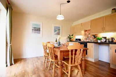 a kitchen with a wooden table and some chairs at Riverside farm cottage on private wildlife estate 1-bedroom in Washaway