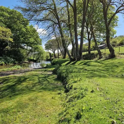 a grassy field with trees and a river at Riverside farm cottage on private wildlife estate 1-bedroom in Washaway