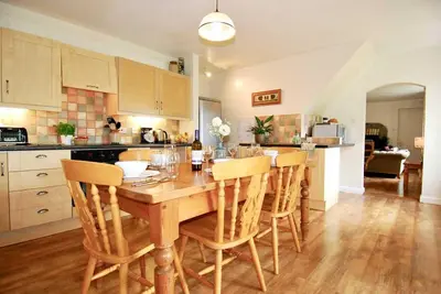 a kitchen with a wooden table and some chairs at Riverside farm cottage on private wildlife estate 1-bedroom in Washaway
