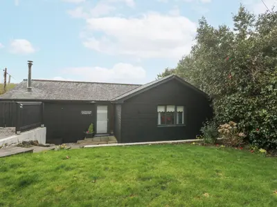 a black house with a green yard at Chy Benyngoth in Hayle