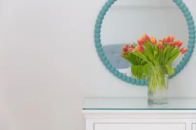 a vase of flowers on a table in front of a mirror at Lowena in St Ives