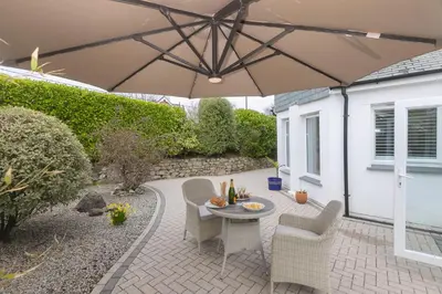 a patio with a table and chairs and an umbrella at Lowena in St Ives