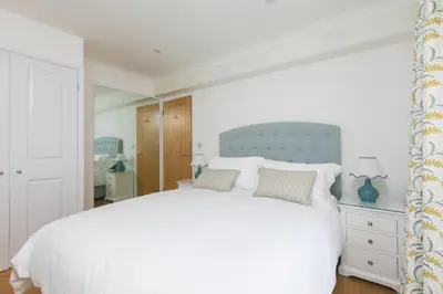 a bedroom with a large white bed with a blue headboard at Lowena in St Ives