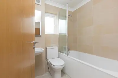 a bathroom with a toilet and a tub and a window at Lowena in St Ives