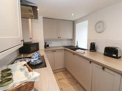 a kitchen with white cabinets and a clock on the wall at Anneth Lowen in Hayle