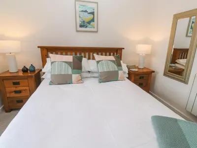 a bedroom with a white bed with pillows and a mirror at Anneth Lowen in Hayle