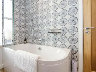 a white tub in a bathroom with a wallpaper at The Haven in Marazion