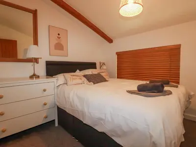 a bedroom with a white bed with a dresser and a window at Tincroft in Truro