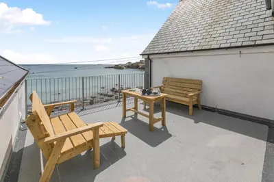 a patio with two benches and a table on a balcony at 3 Bed in Coverack oc-b31082 in Coverack