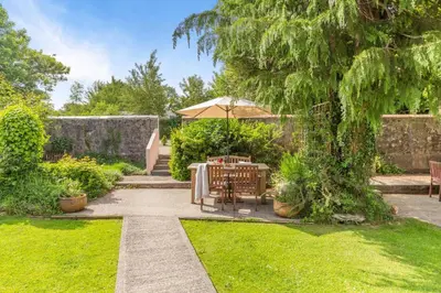 a patio with a table and an umbrella in a garden at 2 Bed in Launceston oc-f30999 in Lewannick