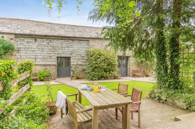 a wooden table and chairs in a garden at 2 Bed in Launceston oc-g31003 in Lewannick