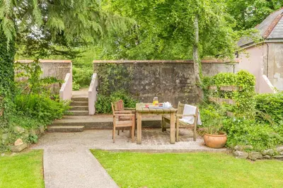 a table and chairs in a garden with stairs at 2 Bed in Launceston oc-g31003 in Lewannick