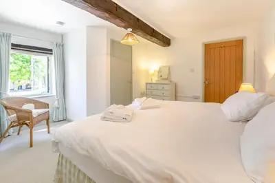 a bedroom with a large white bed and a chair at 3 Bed in Launceston oc-l31001 in Lewannick