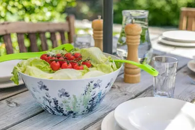 a bowl of lettuce and tomatoes on a wooden table at 3 Bed in Launceston oc-l31001 in Lewannick