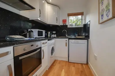 a kitchen with white cabinets and a washer and dryer at Trenethick in Truro