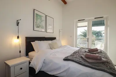 a bedroom with a large white bed with a window at Treveglos in Truro