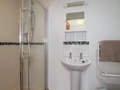 a white bathroom with a sink and a shower at Treveglos in Truro