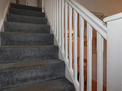 a staircase with grey carpeting and white railings at Tregullan in Truro