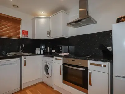 a kitchen with white cabinets and a washer and dryer at Tregullan in Truro