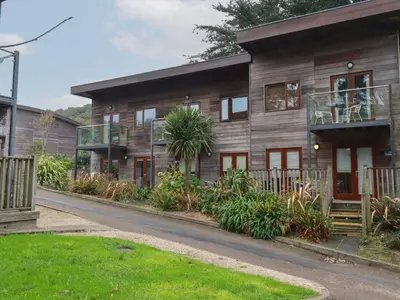 a wooden house with a balcony and a yard at Treburgett in Truro