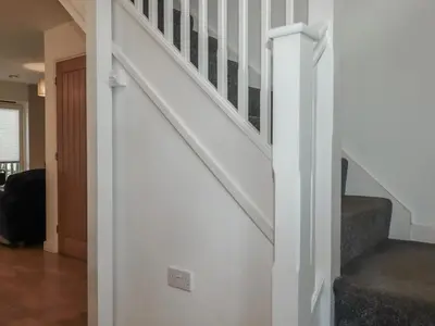 a white staircase in a living room with a stair case at Treburgett in Truro
