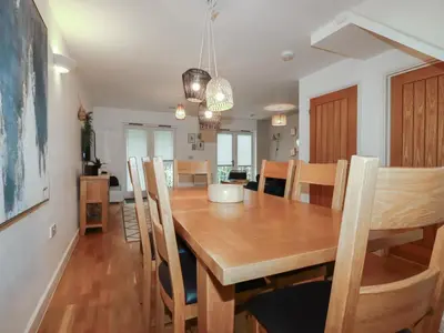 a dining room and kitchen with a wooden table and chairs at Treburgett in Truro