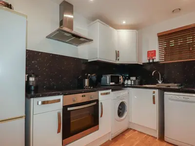 a kitchen with white cabinets and a washer and dryer at Treburgett in Truro