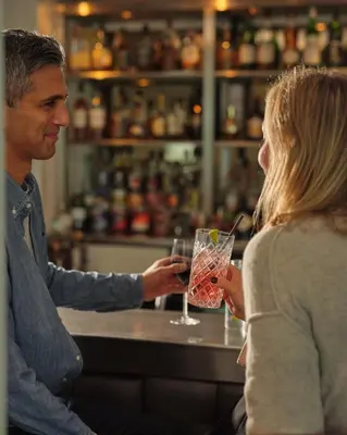 a man and a woman sitting at a bar with a drink at St Moritz Hotel Houses in Polzeath
