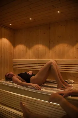 a woman laying on a bed in a sauna at St Moritz Hotel Houses in Polzeath