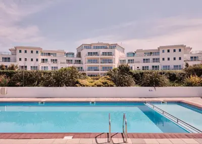 a swimming pool with buildings in the background at St Moritz Hotel Houses in Polzeath