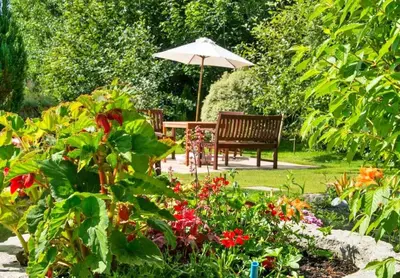 a garden with a bench and an umbrella and flowers at Finest Retreats - Orchard View in Hayle