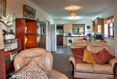a living room with two leather couches and a kitchen at Finest Retreats - Orchard View in Hayle