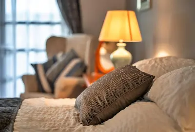 a bed with a pillow and a chair and a lamp at Finest Retreats - Orchard View in Hayle