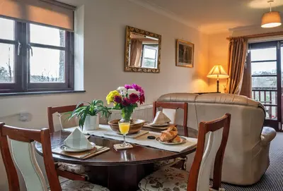 a dining room with a table with flowers on it at Finest Retreats - Orchard View in Hayle